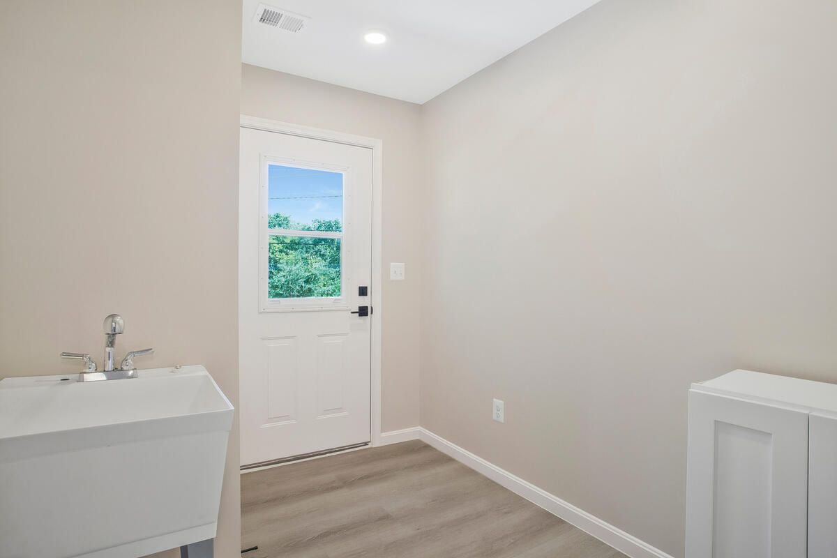A laundry room with a sink and a door.