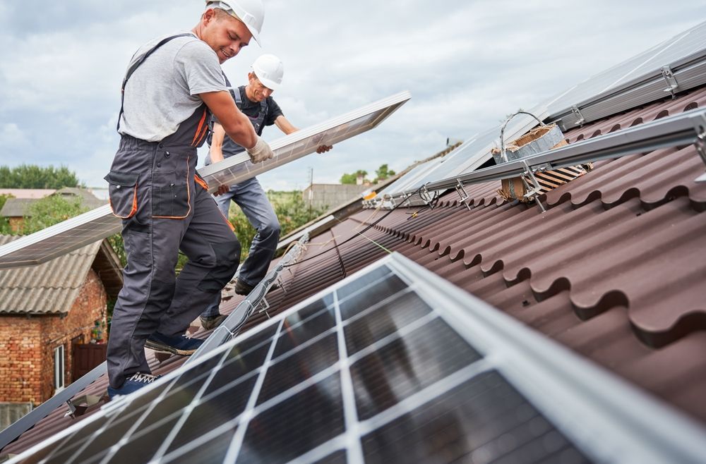 two men are installing solar panels on the roof of a house .