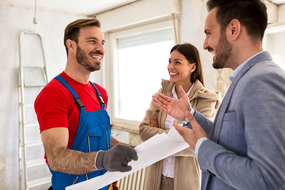 a man in overalls is talking to a woman and a man in a suit .