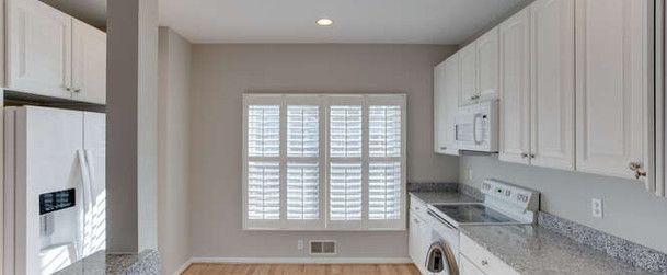 a kitchen with white cabinets , a refrigerator , a washer and dryer , and a window .