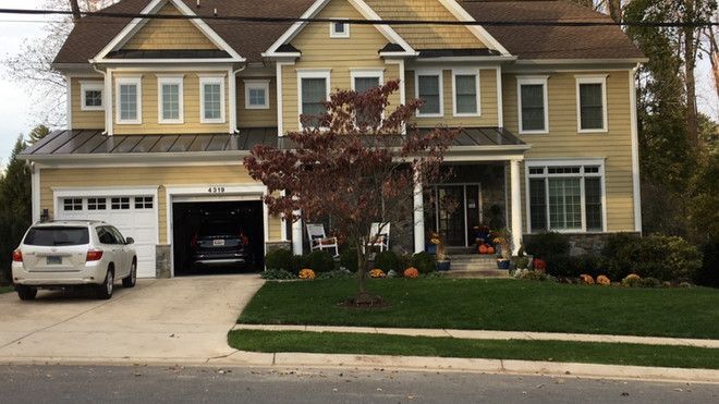 a large yellow house with a car parked in front of it .