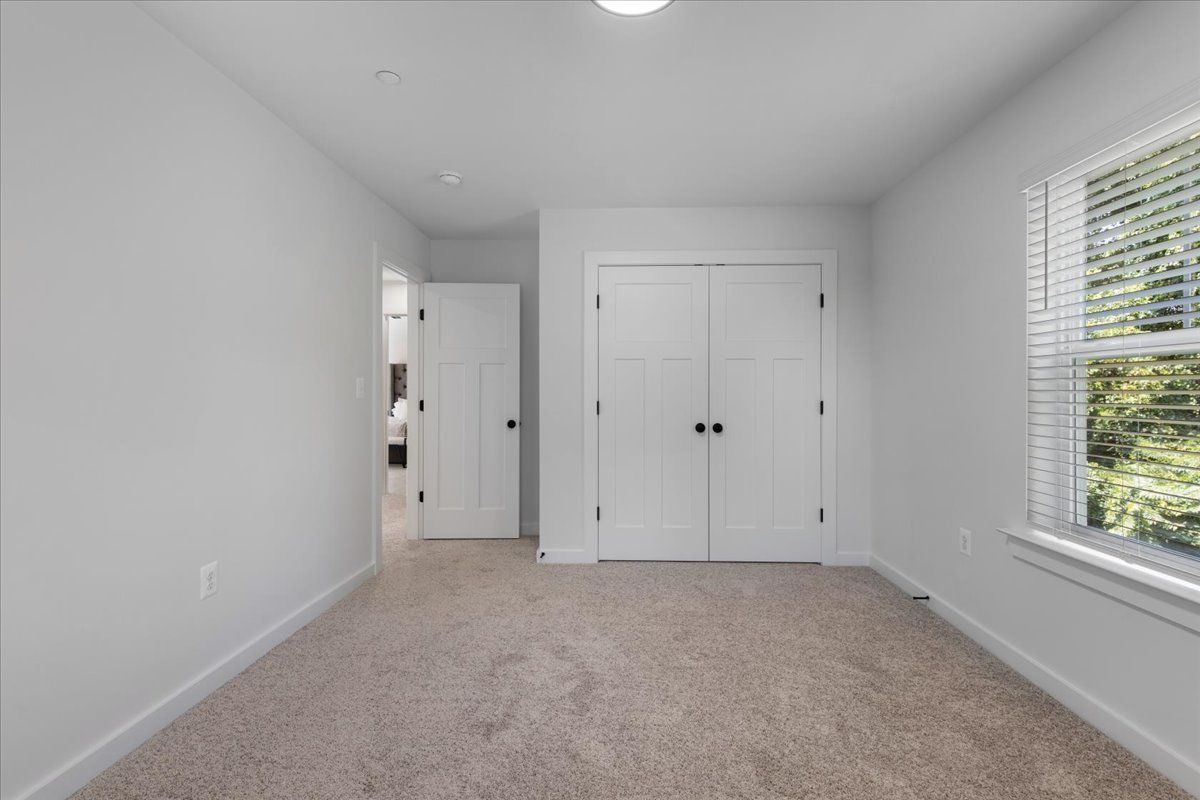 An empty bedroom with a window and a closet.