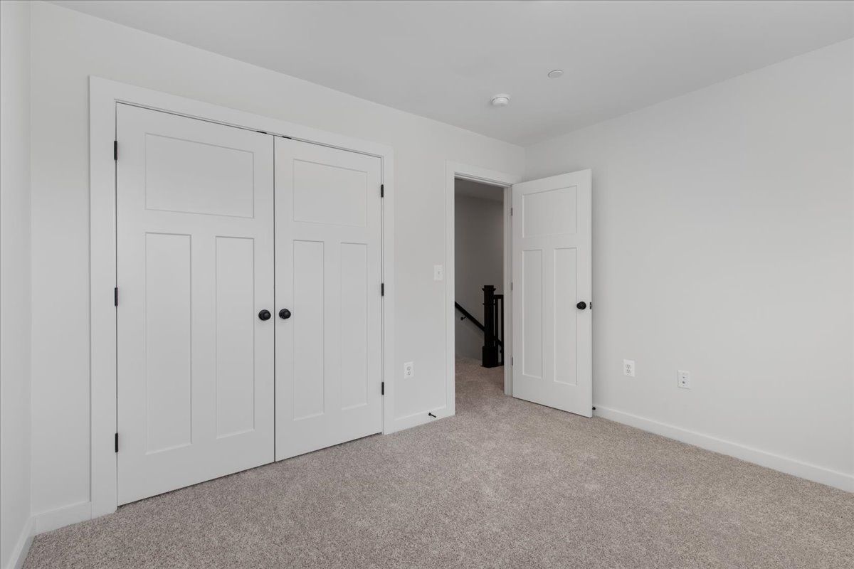 An empty bedroom with a carpeted floor and white walls.