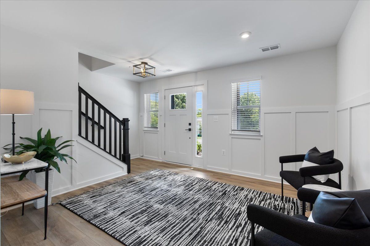 A living room with a rug , chairs and stairs.