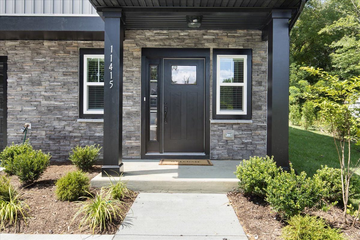 The front of a house with a black door and a porch.
