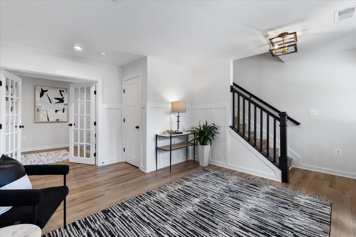 A living room with a rug , chair , table and stairs.