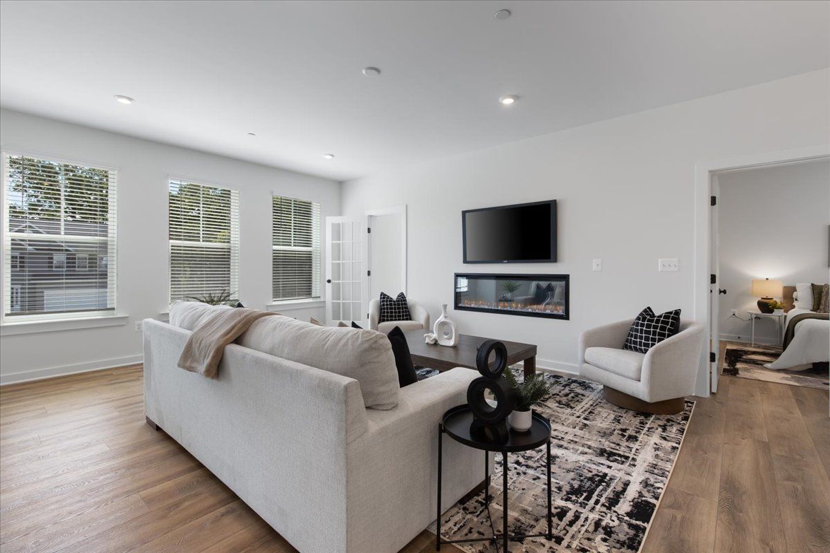 A living room with a couch , chair , television and fireplace.