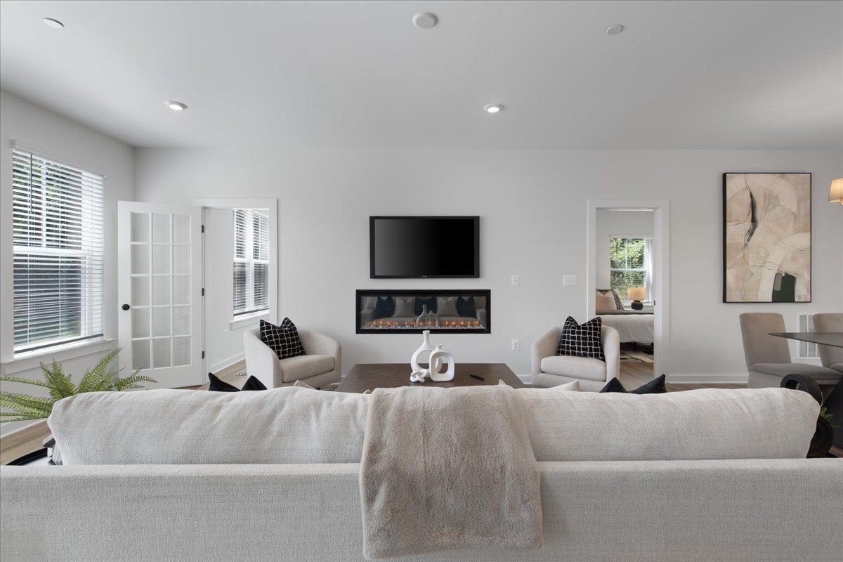 A living room with a white couch and a flat screen tv on the wall.