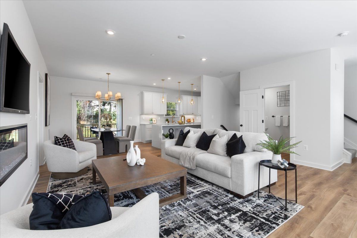 A living room with a couch , chairs , coffee table and television.
