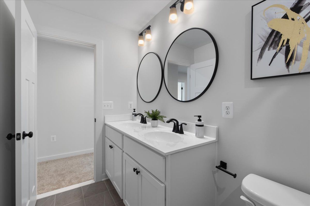 A bathroom with two sinks , two mirrors and a toilet.