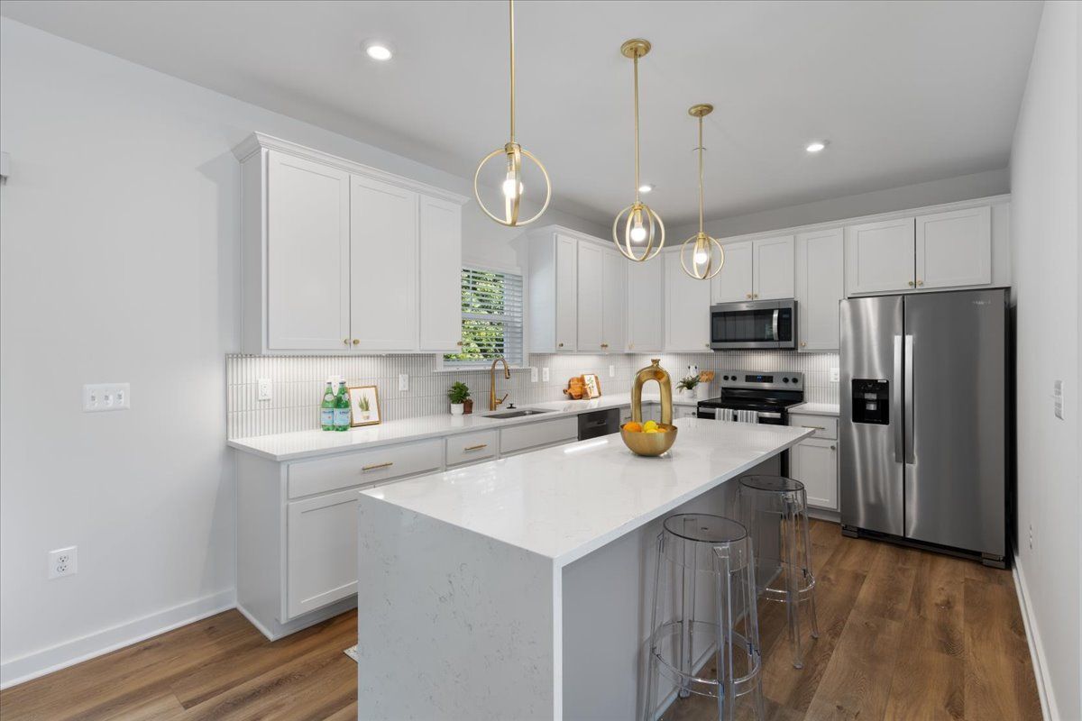 A kitchen with white cabinets , stainless steel appliances , and a large island.