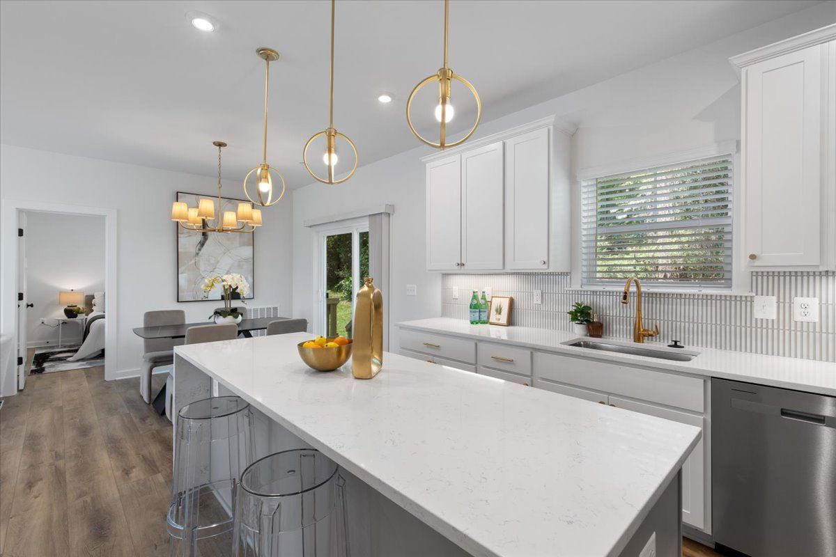 A kitchen with white cabinets and stainless steel appliances and a large island.
