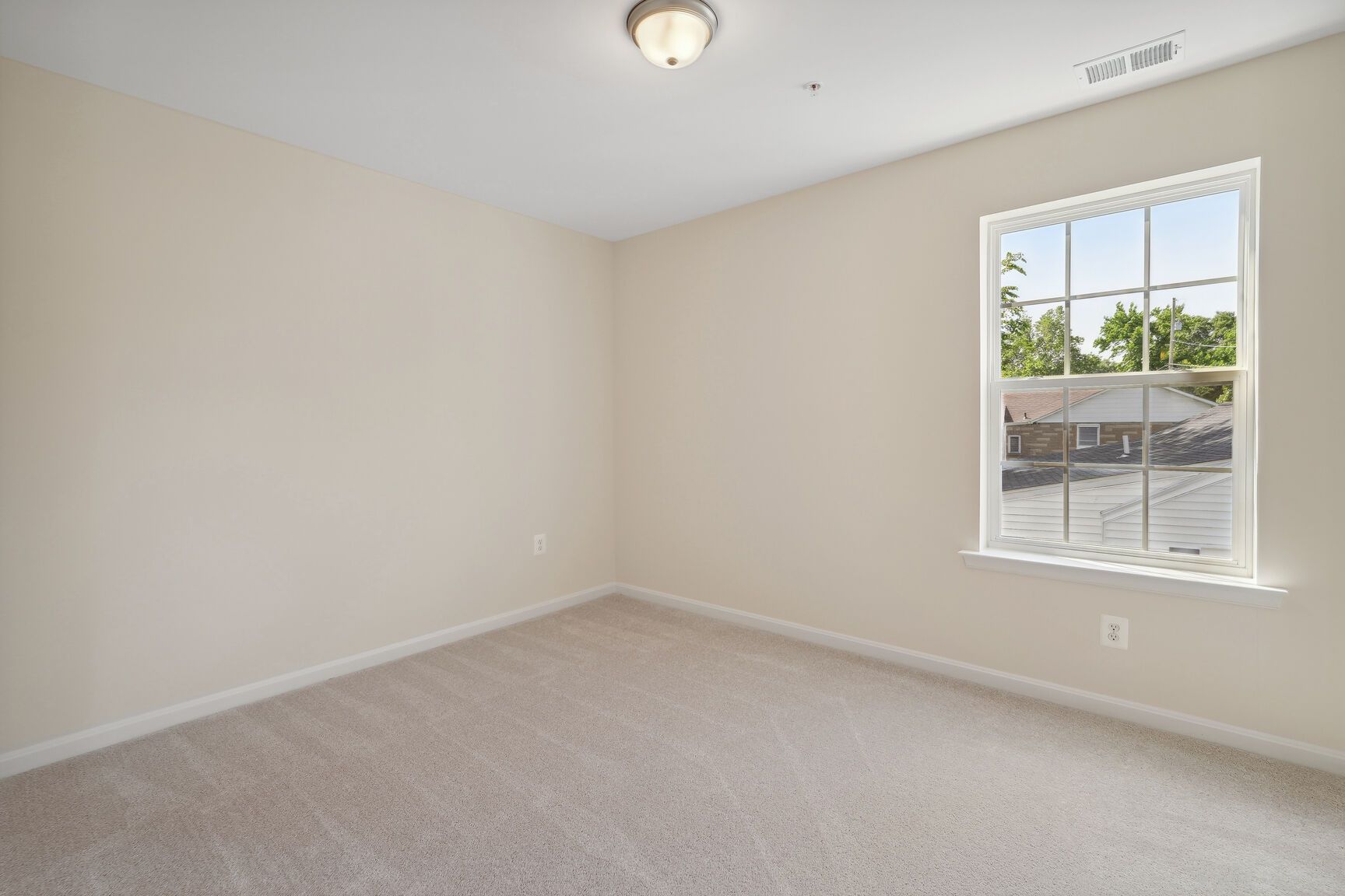 An empty bedroom with a window and a ceiling fan.