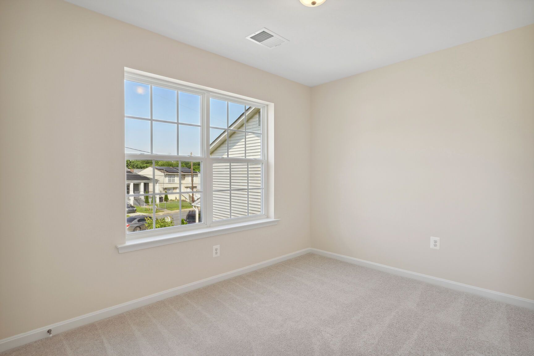 An empty bedroom with a large window and a ceiling fan.