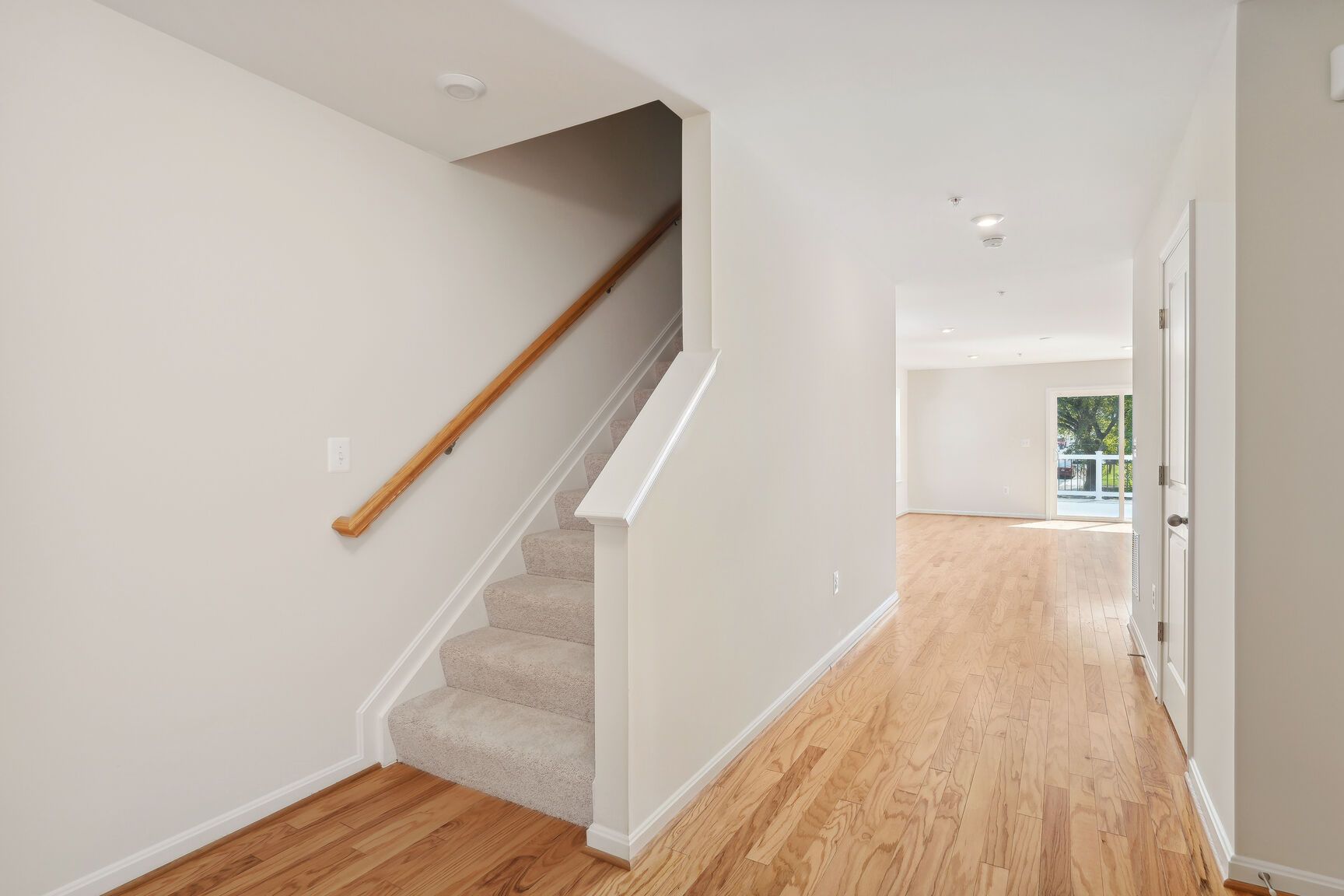 An empty hallway with hardwood floors and stairs
