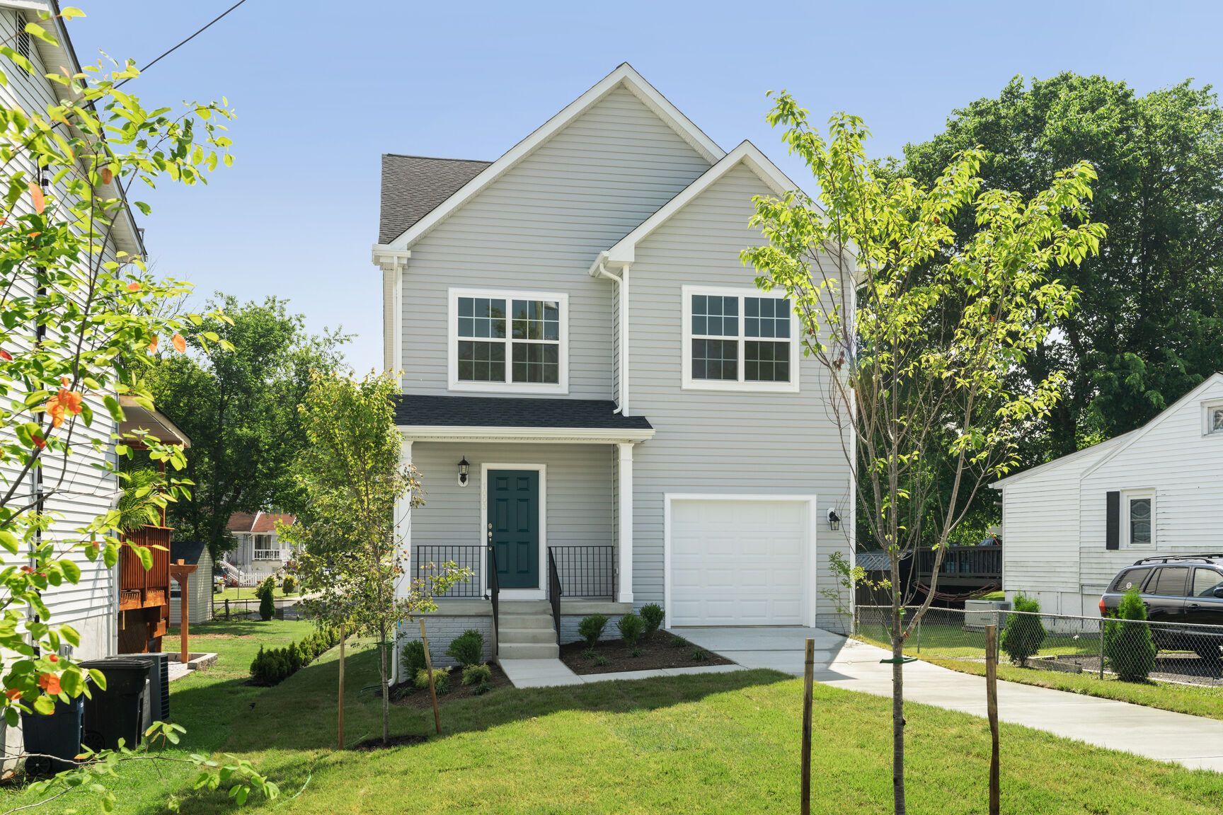 A gray house with a white garage and a green door