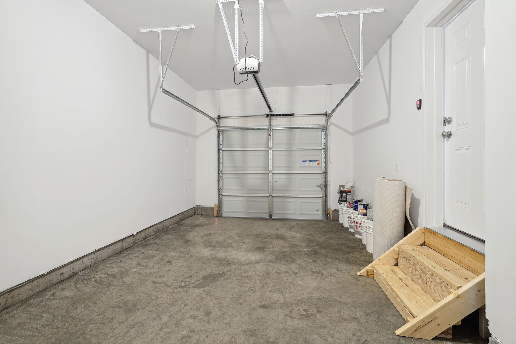 An empty garage with a garage door open and a wooden ramp.
