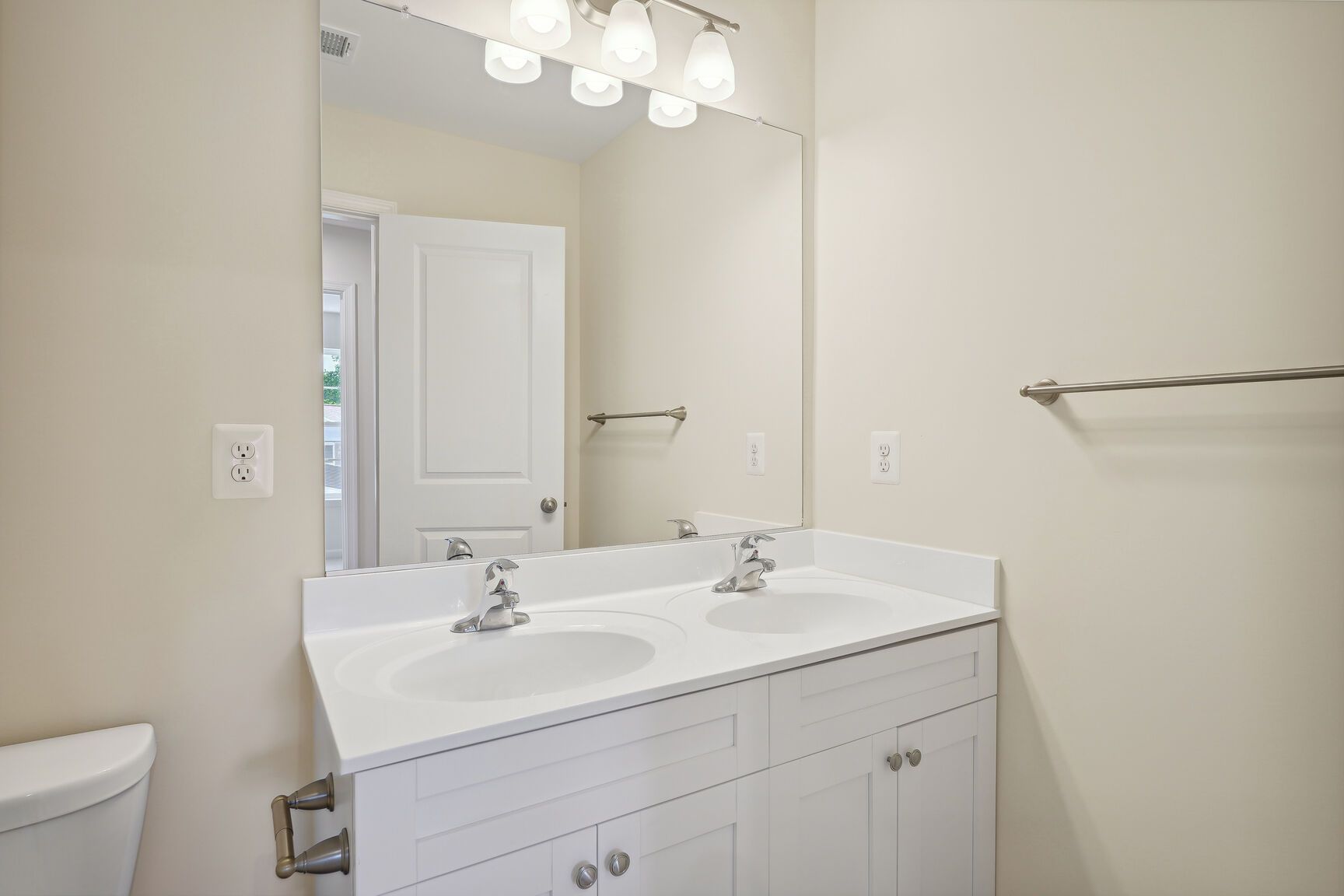 A bathroom with two sinks , a toilet and a mirror.