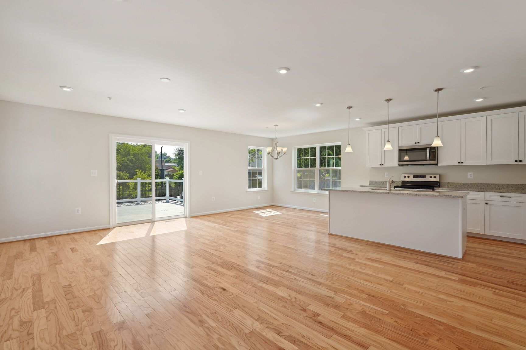 A large empty room with hardwood floors and a kitchen.