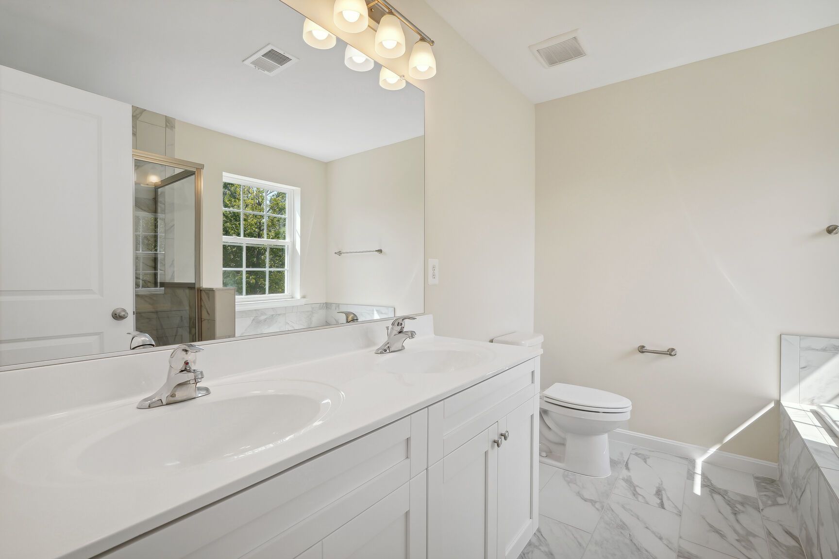 A bathroom with two sinks , a toilet , and a large mirror.
