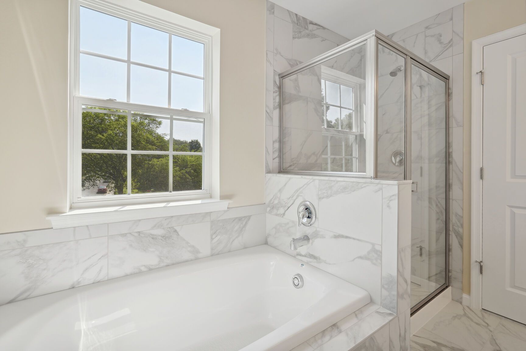 A bathroom with a tub , shower , and window.