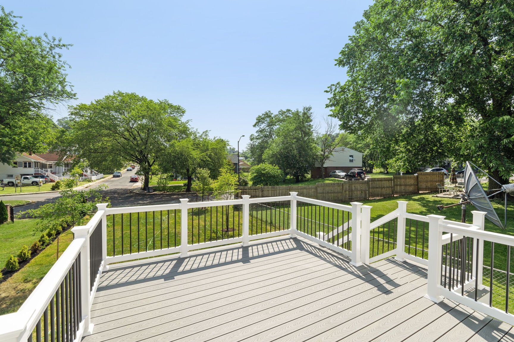 A deck with a white railing and trees in the background