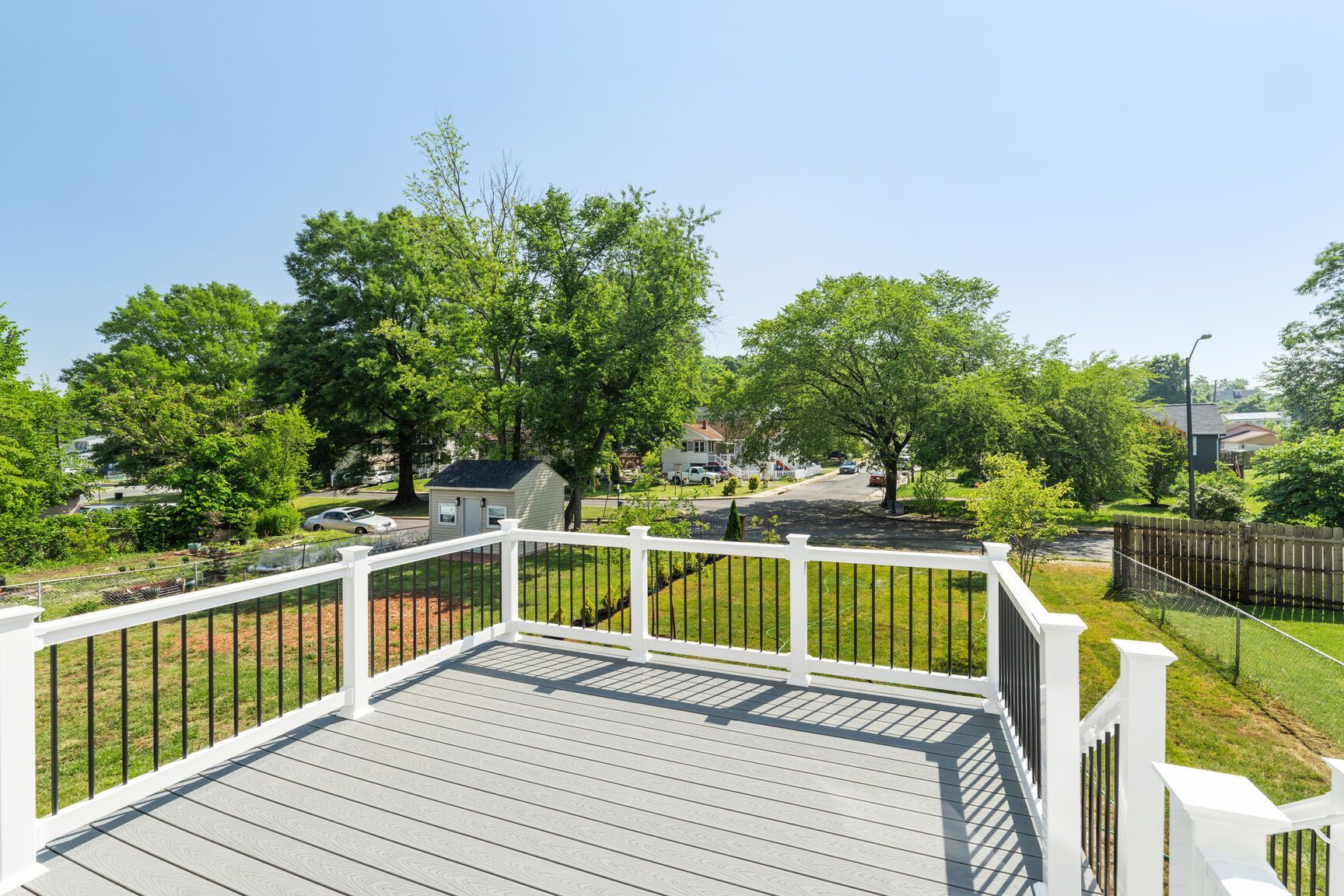 A large deck with a white railing overlooking a lush green field.
