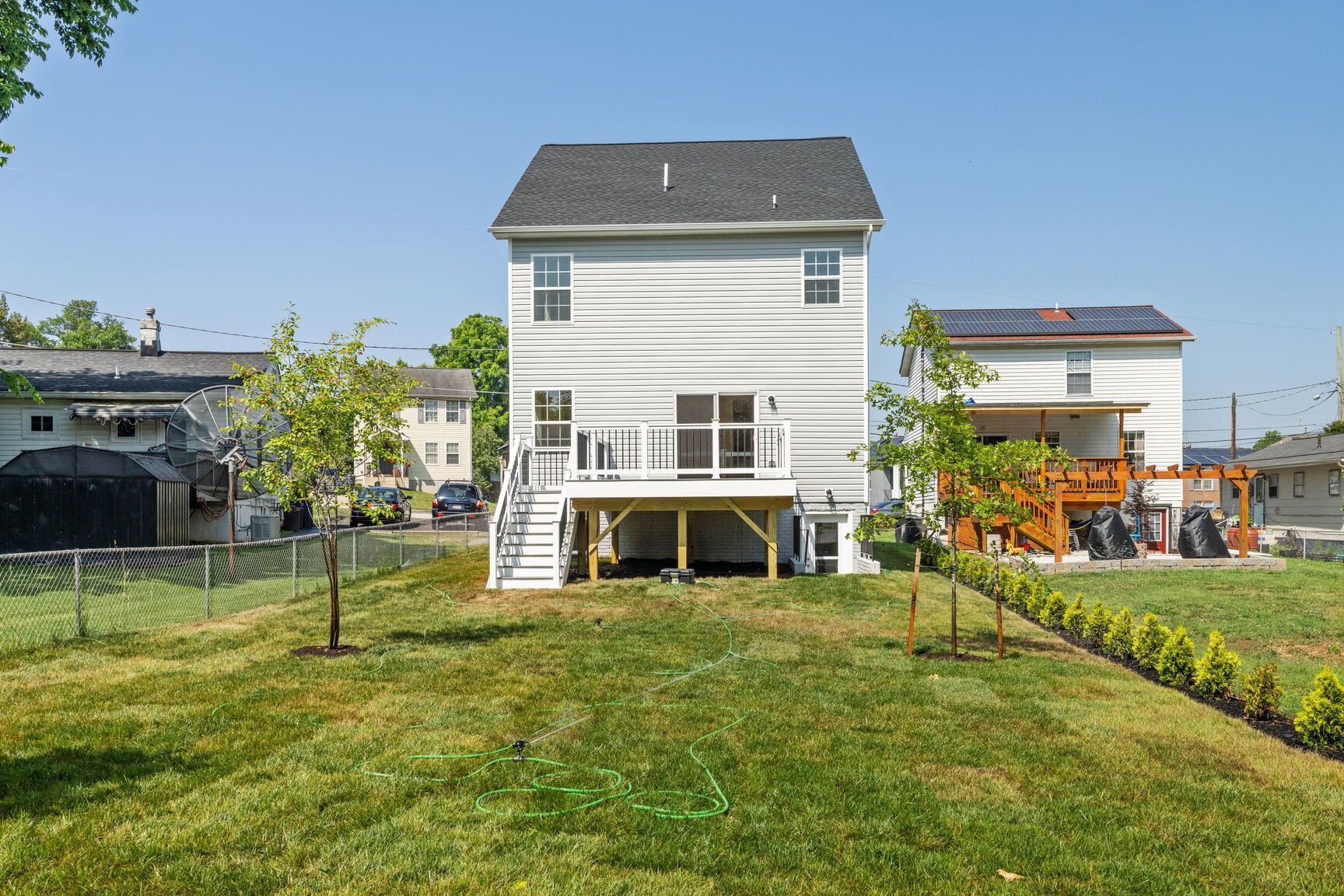 The back of a white house with a large lawn in front of it.