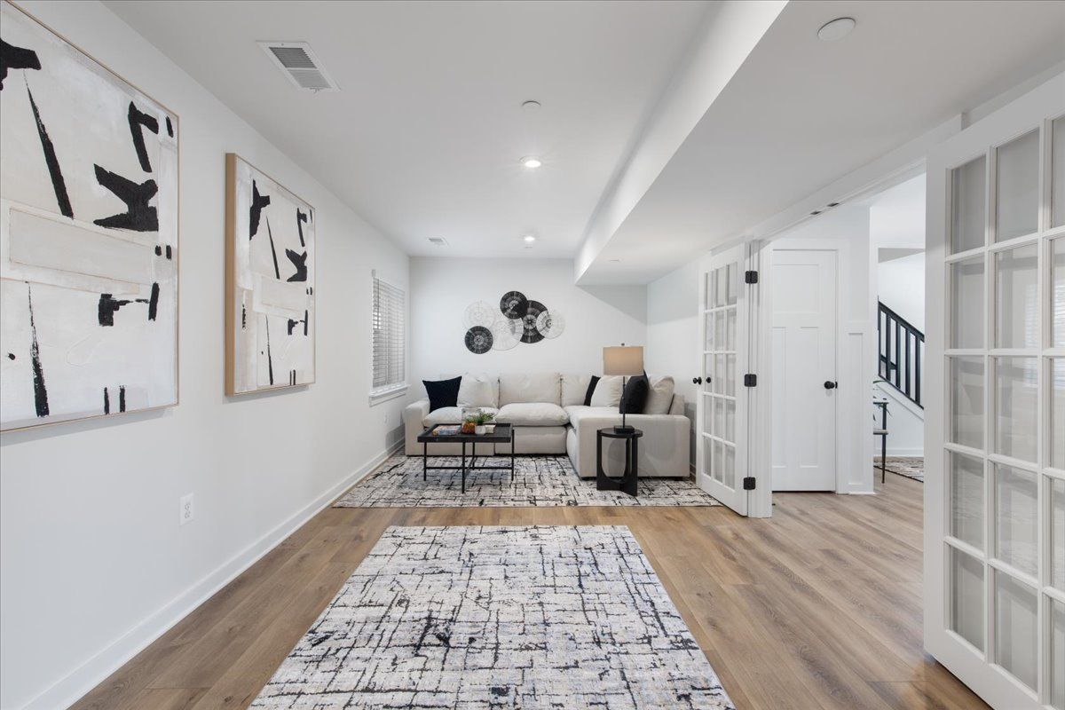 A living room with a couch , rug and paintings on the wall.