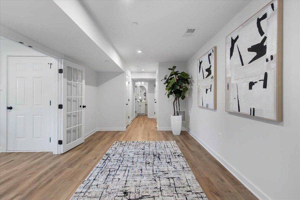 A hallway with a rug and paintings on the wall.