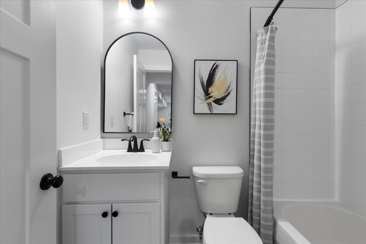 A bathroom with a toilet , sink , mirror and bathtub.