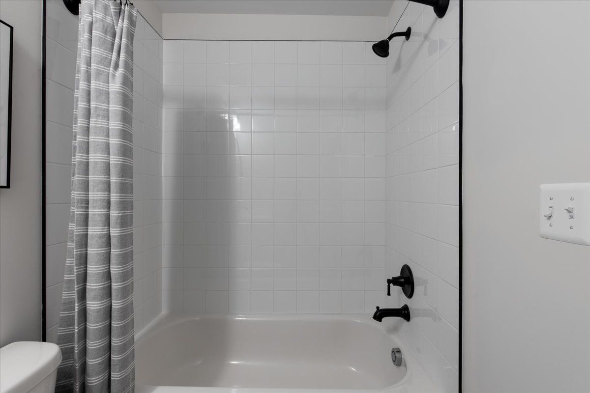 A bathroom with a bathtub , toilet and shower.