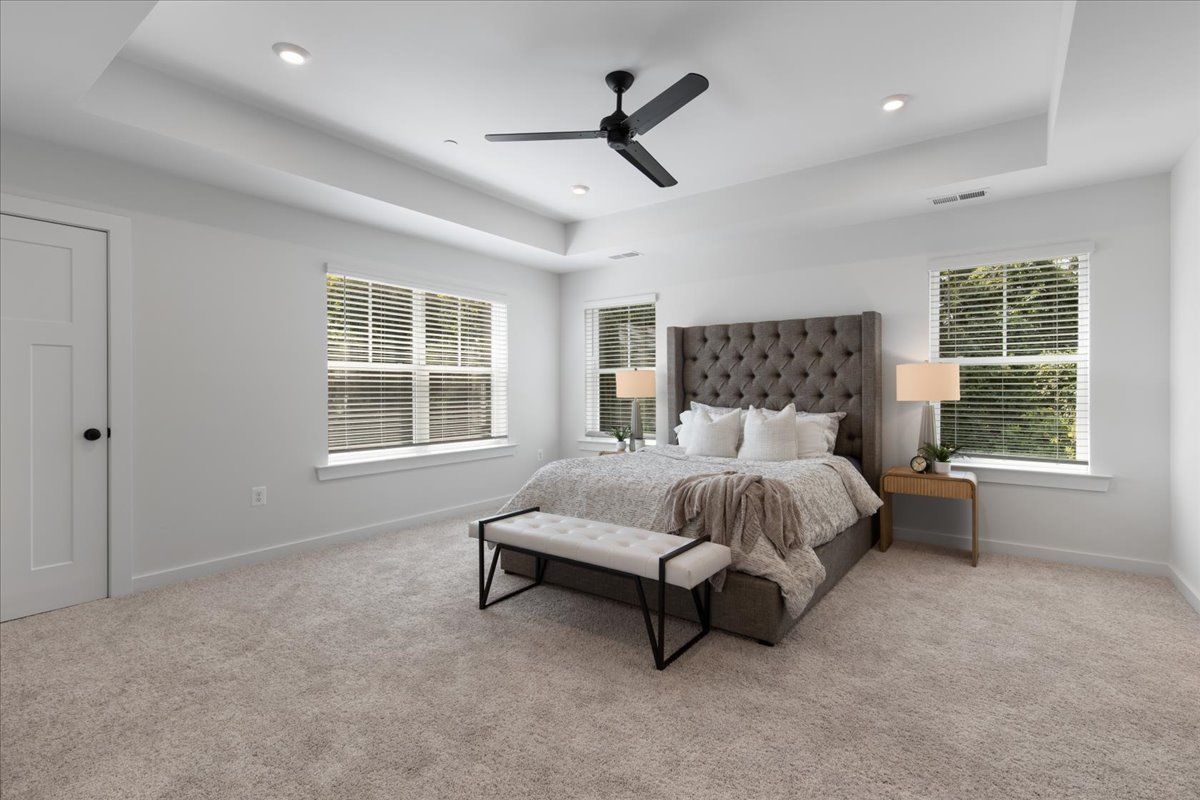 A bedroom with a ceiling fan and a large bed.