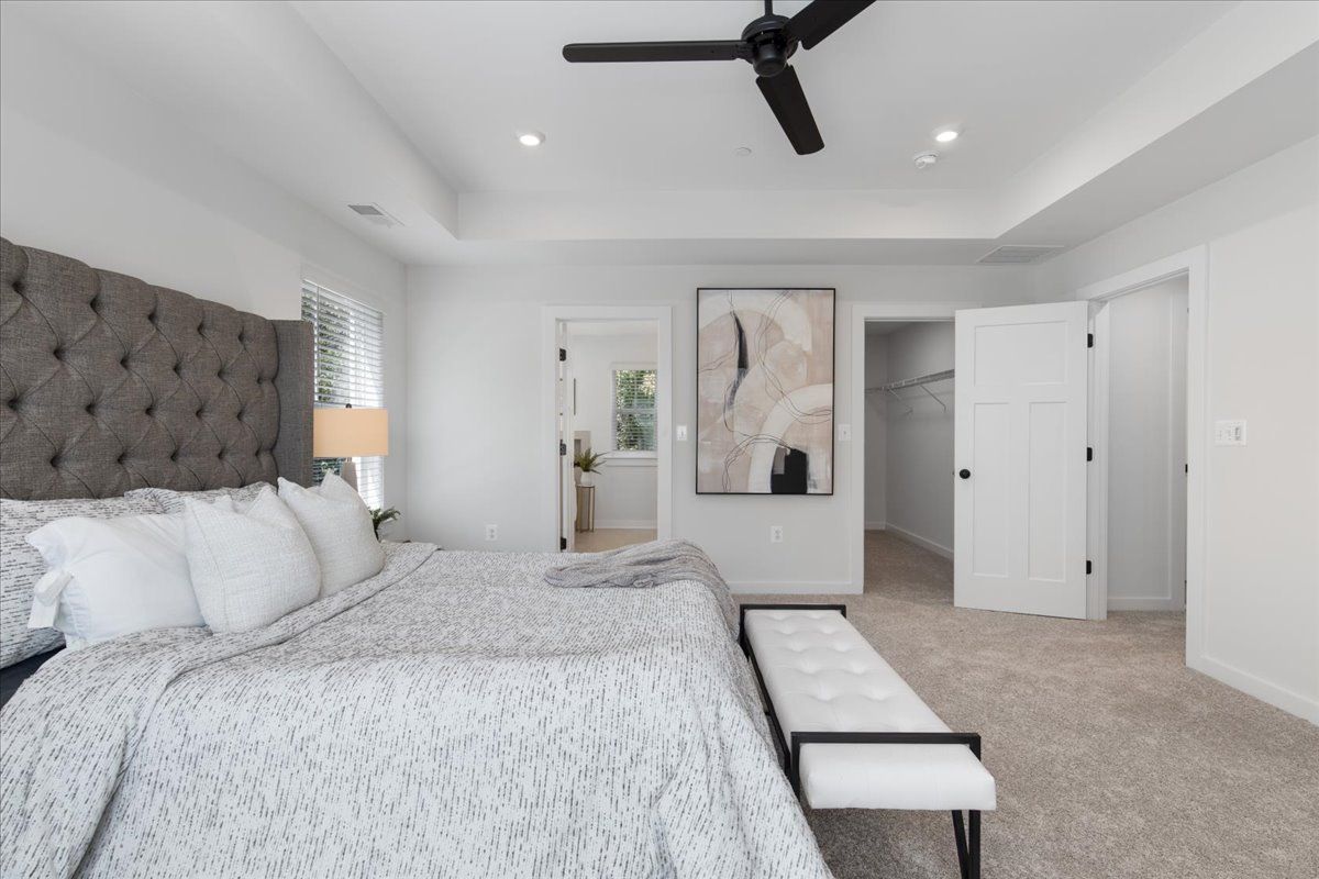 A bedroom with two beds , a bench and a ceiling fan.