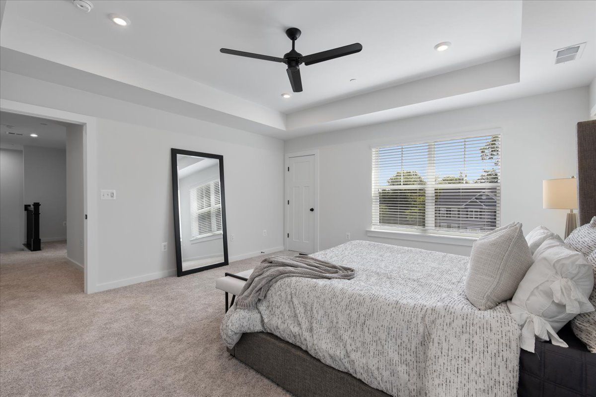 A bedroom with a large bed and a ceiling fan.