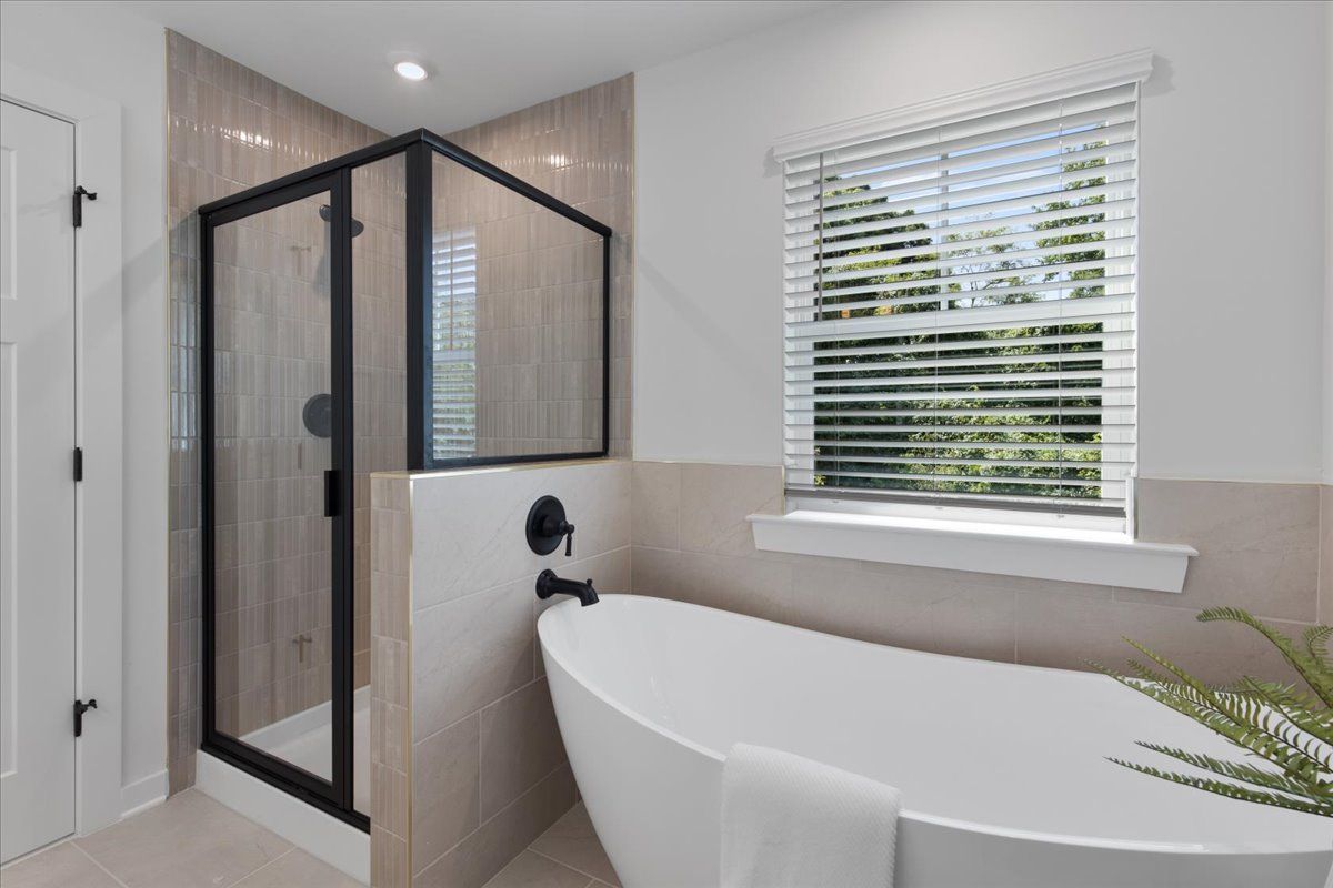 A bathroom with a tub , shower , and window.