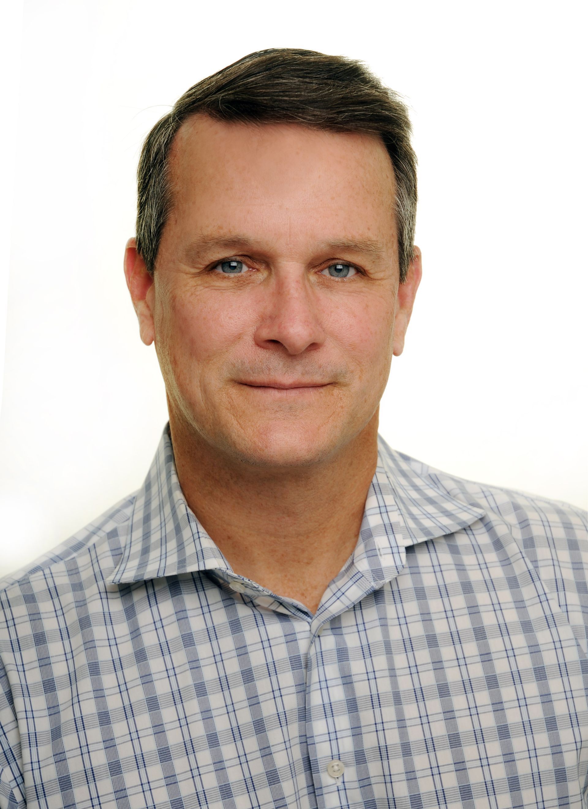 A man wearing a plaid shirt is smiling for the camera.