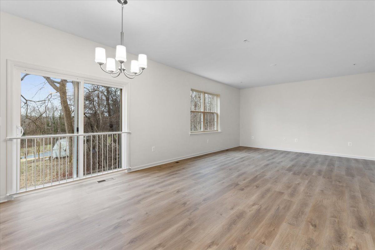 An empty living room with hardwood floors and a chandelier.