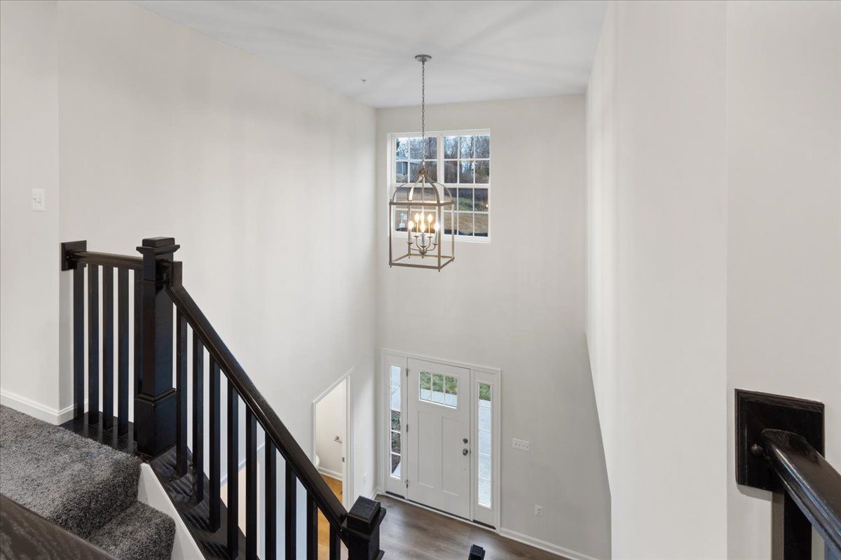 An aerial view of a staircase in a house with a chandelier hanging from the ceiling.