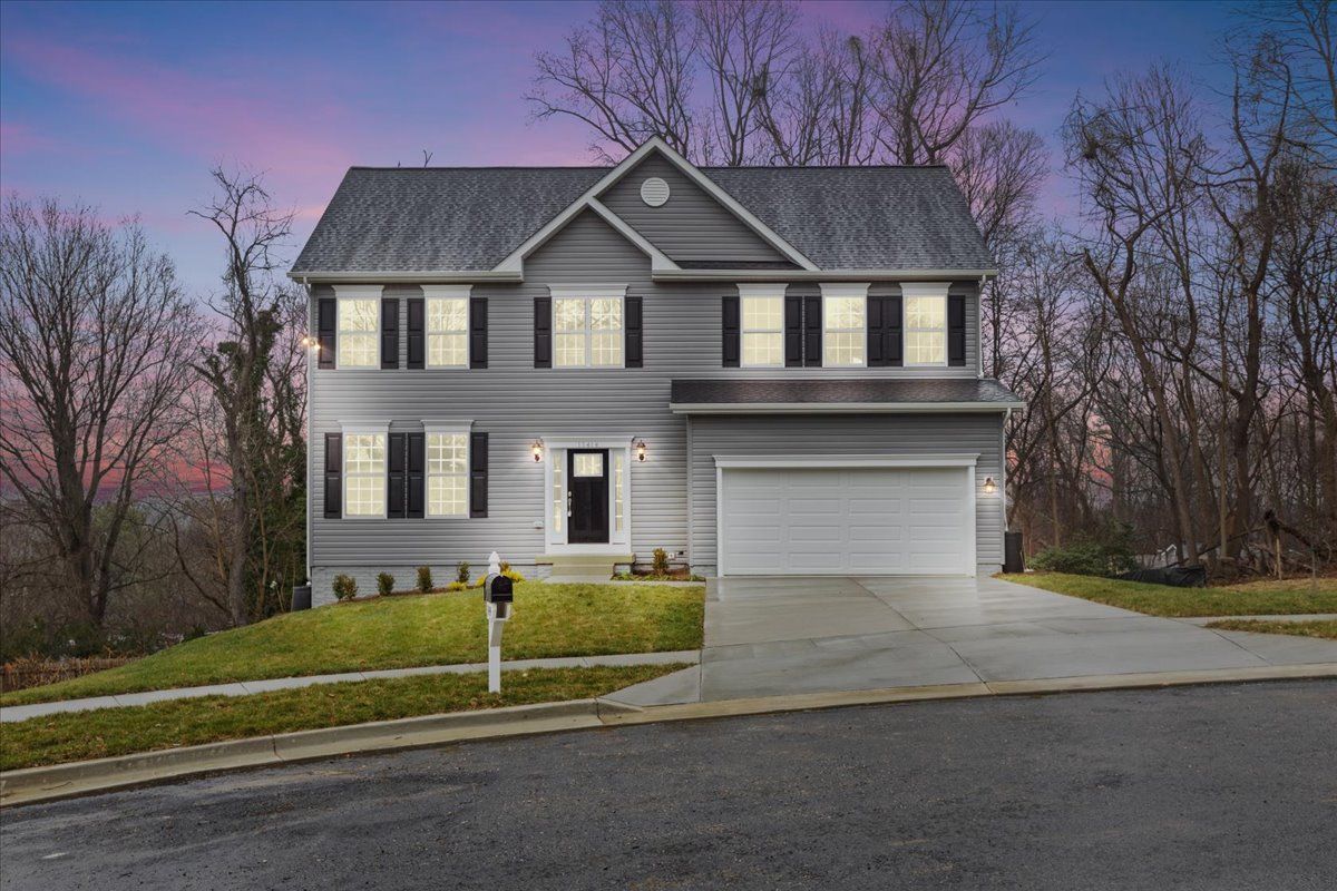 A large house with a garage and a driveway is sitting on top of a hill.