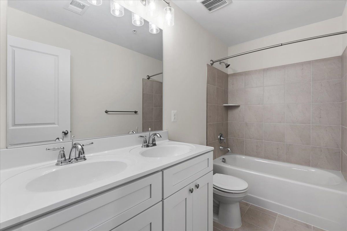 A bathroom with a sink , toilet , tub and mirror.