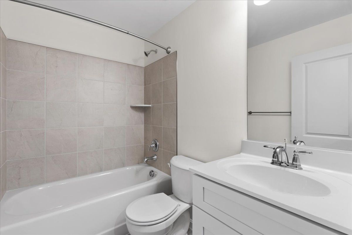 A bathroom with a toilet , sink , bathtub and mirror.