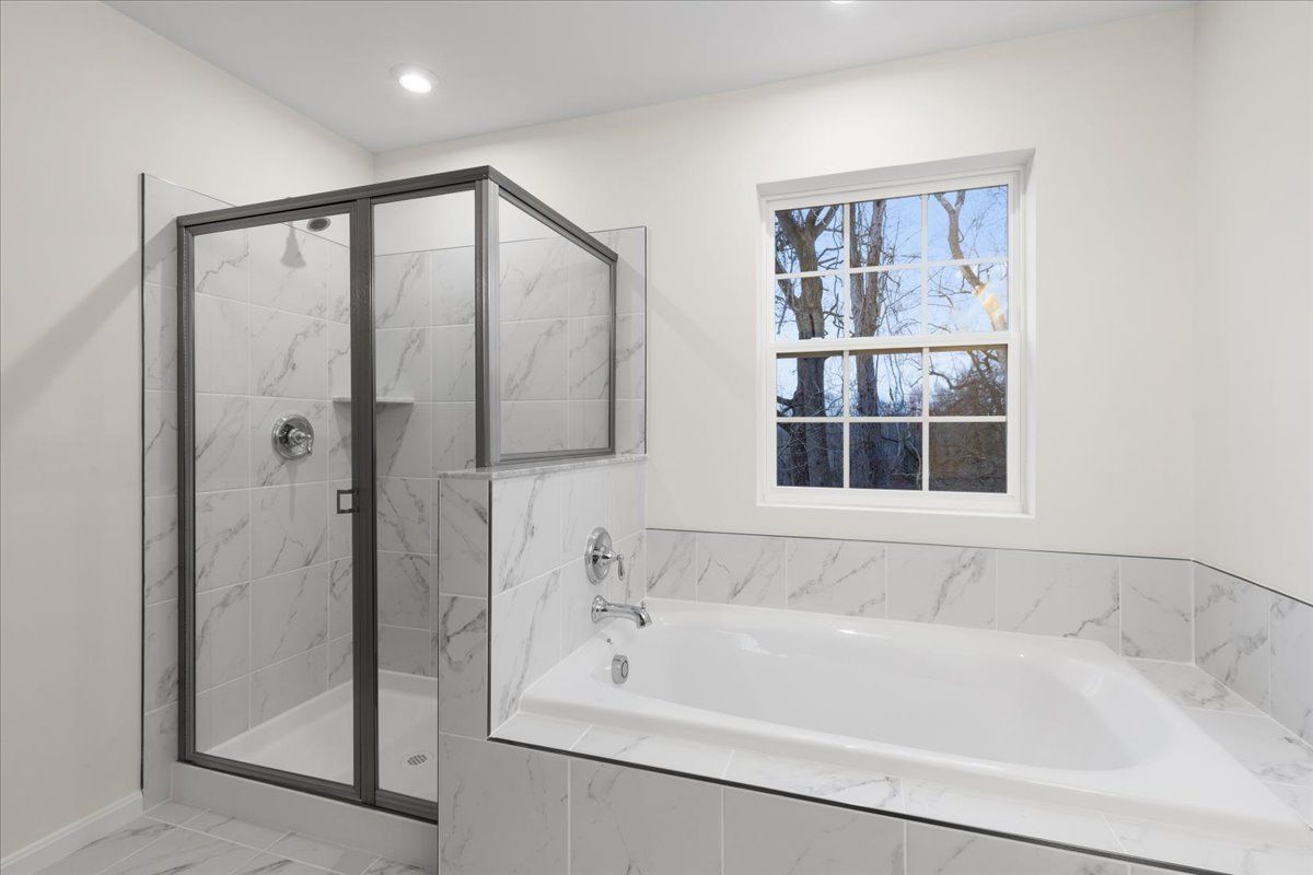 A bathroom with a tub , shower , and window.