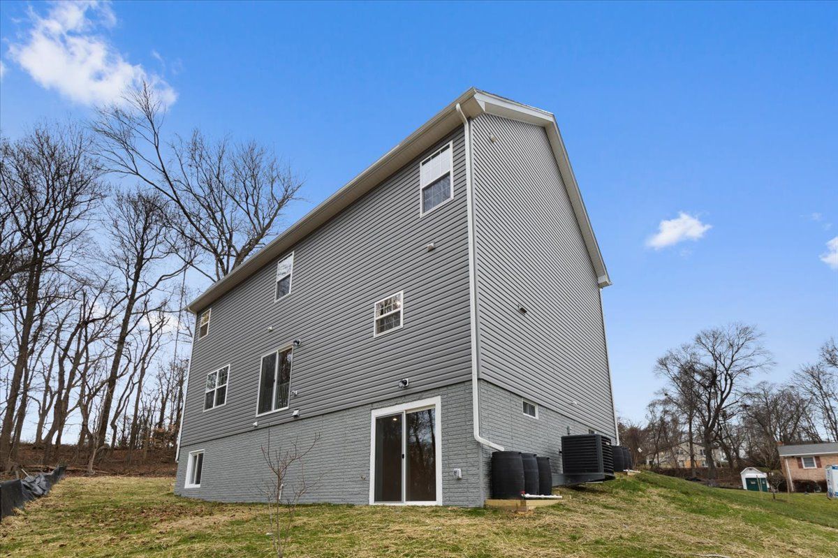 A large house with a sliding glass door is sitting on top of a grassy hill.
