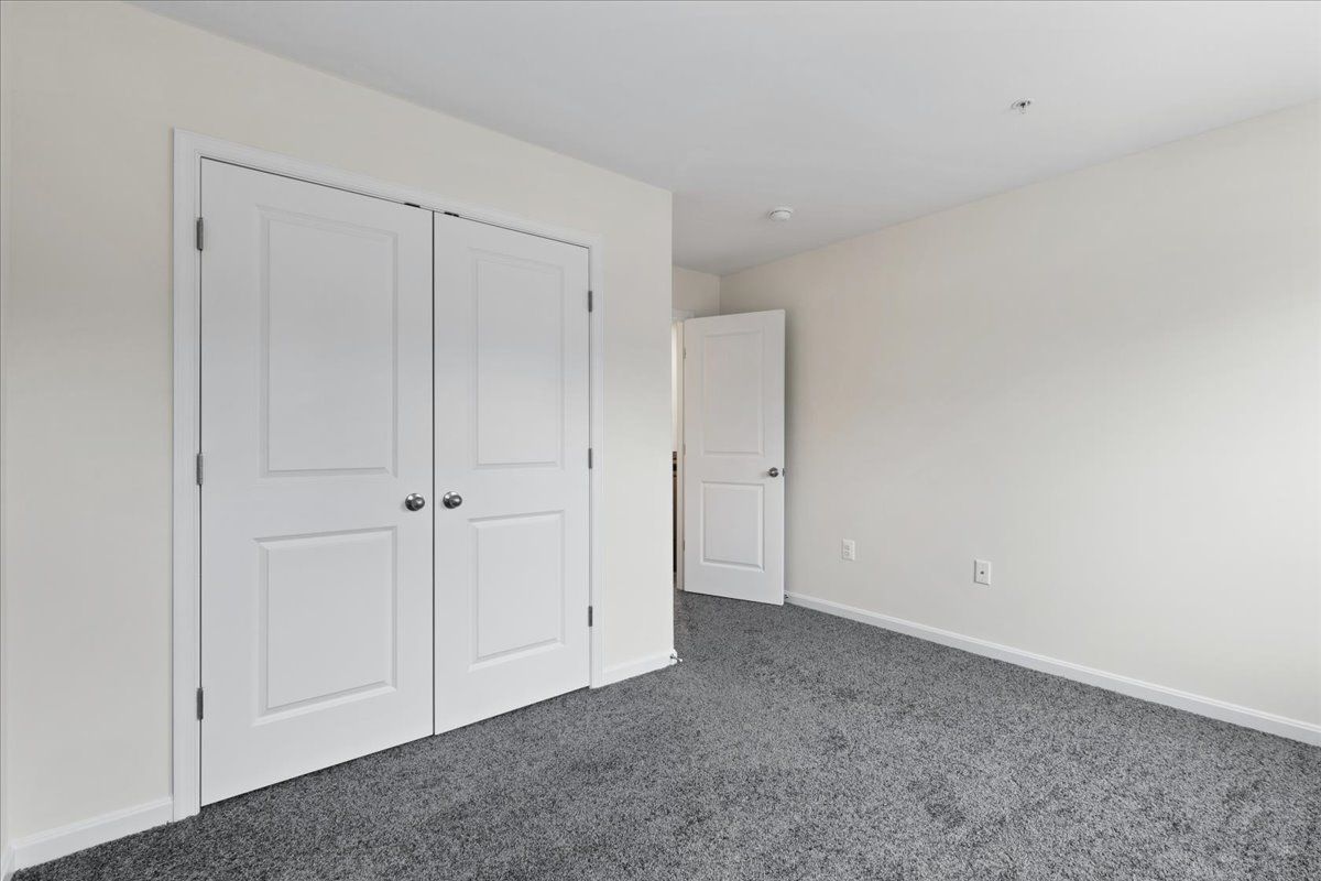 An empty bedroom with a gray carpet and white walls.