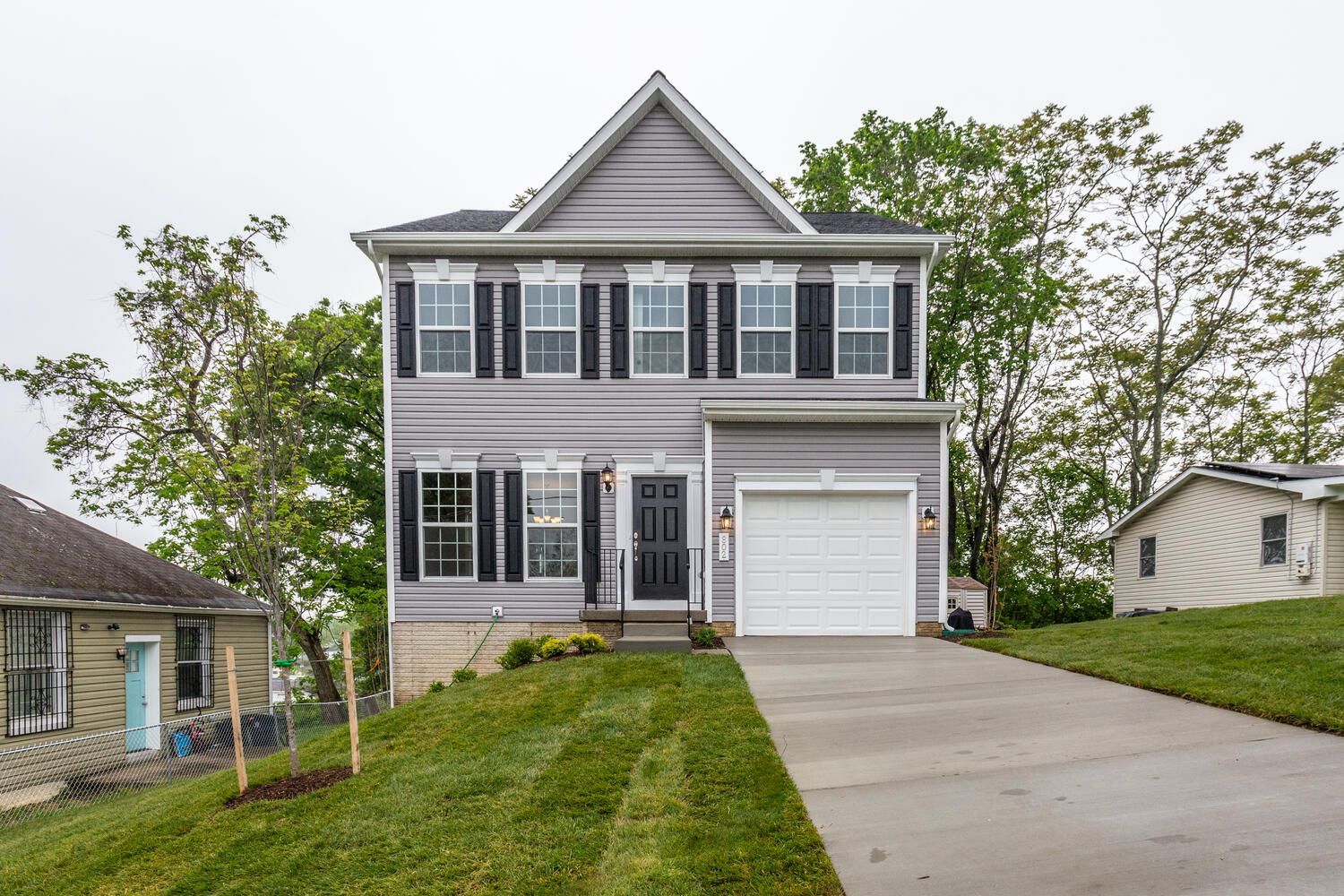 The front of a house with a white garage door and black shutters.