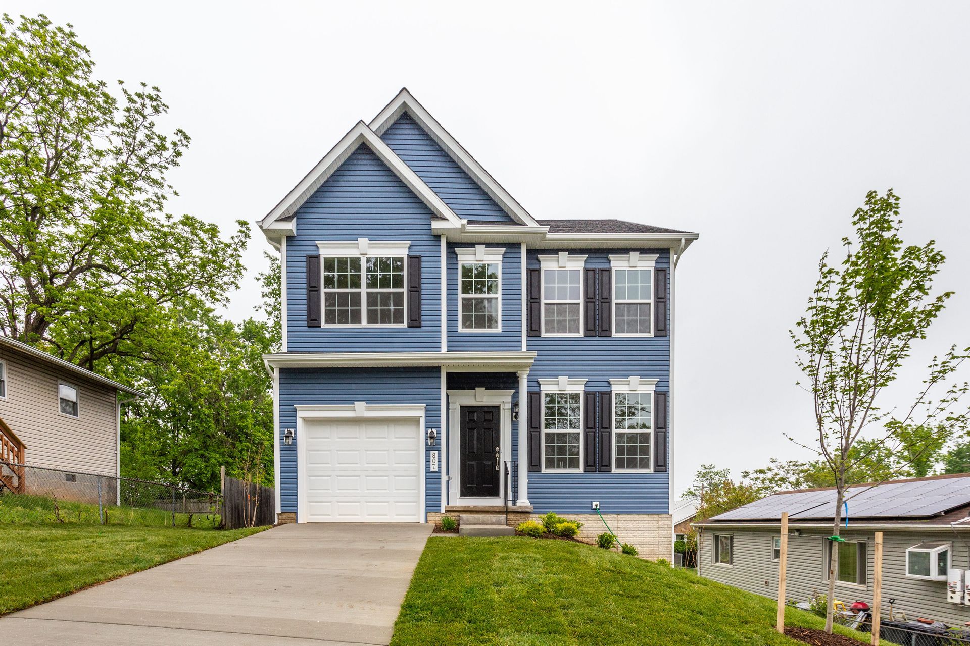 A blue house with white shutters and a white garage door