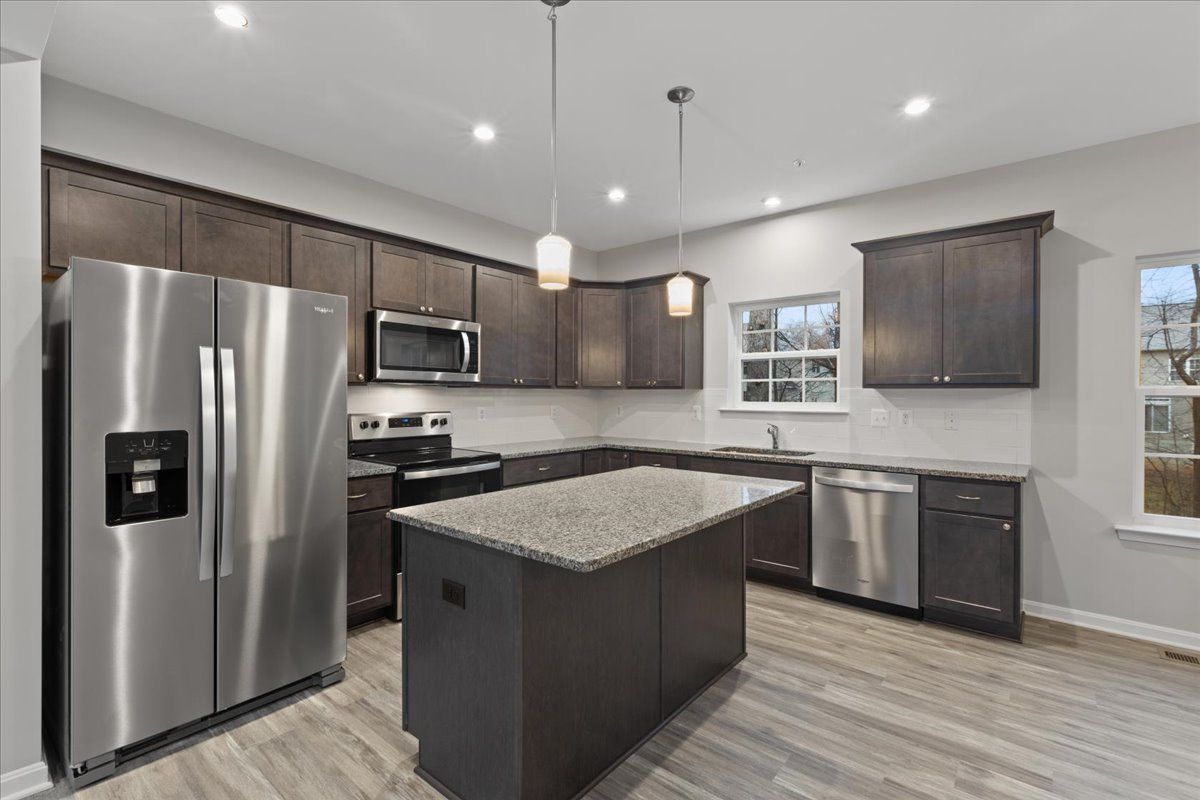 A kitchen with stainless steel appliances , granite counter tops , and a large island.