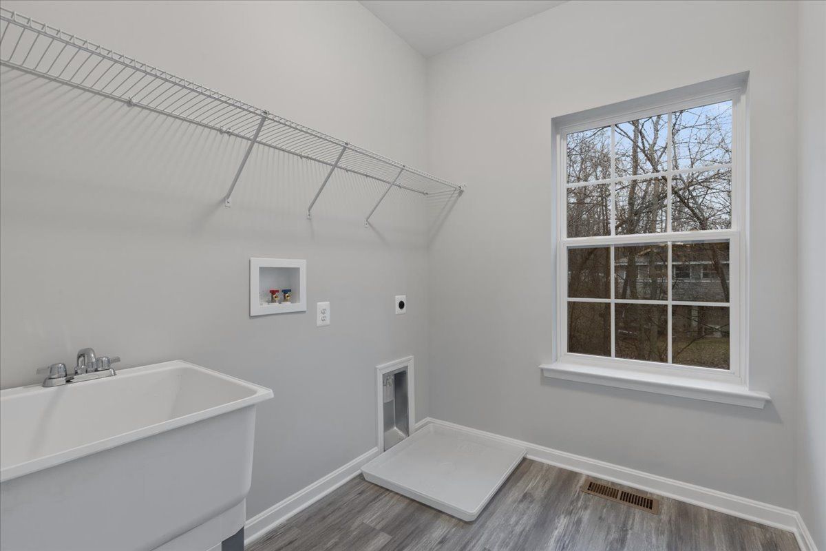 A laundry room with a sink and a window.