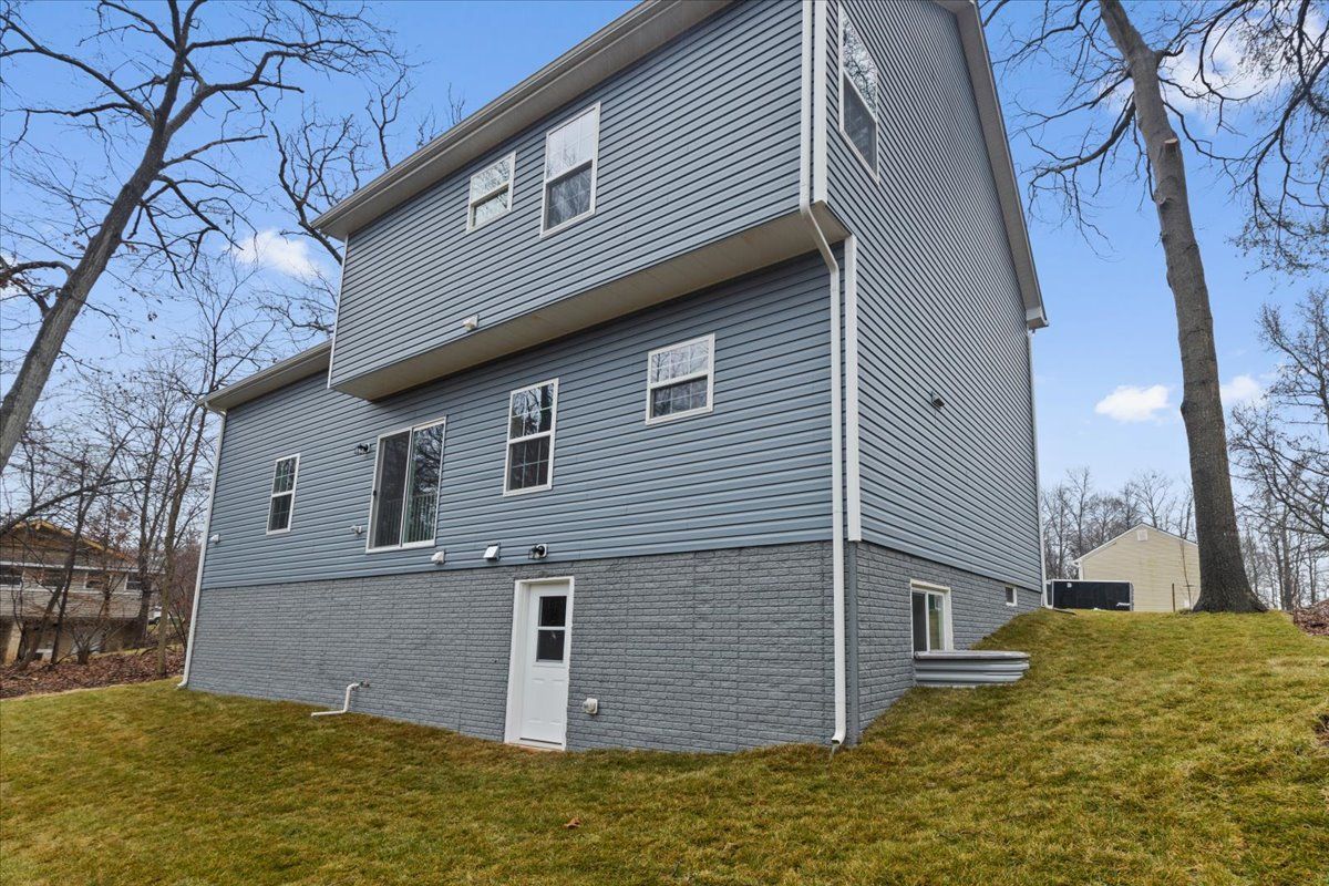 A large house with a lot of windows is sitting on top of a grassy hill.